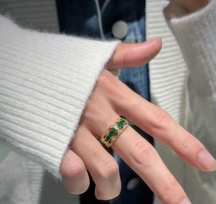 Open band ring with green stones, worn on hand