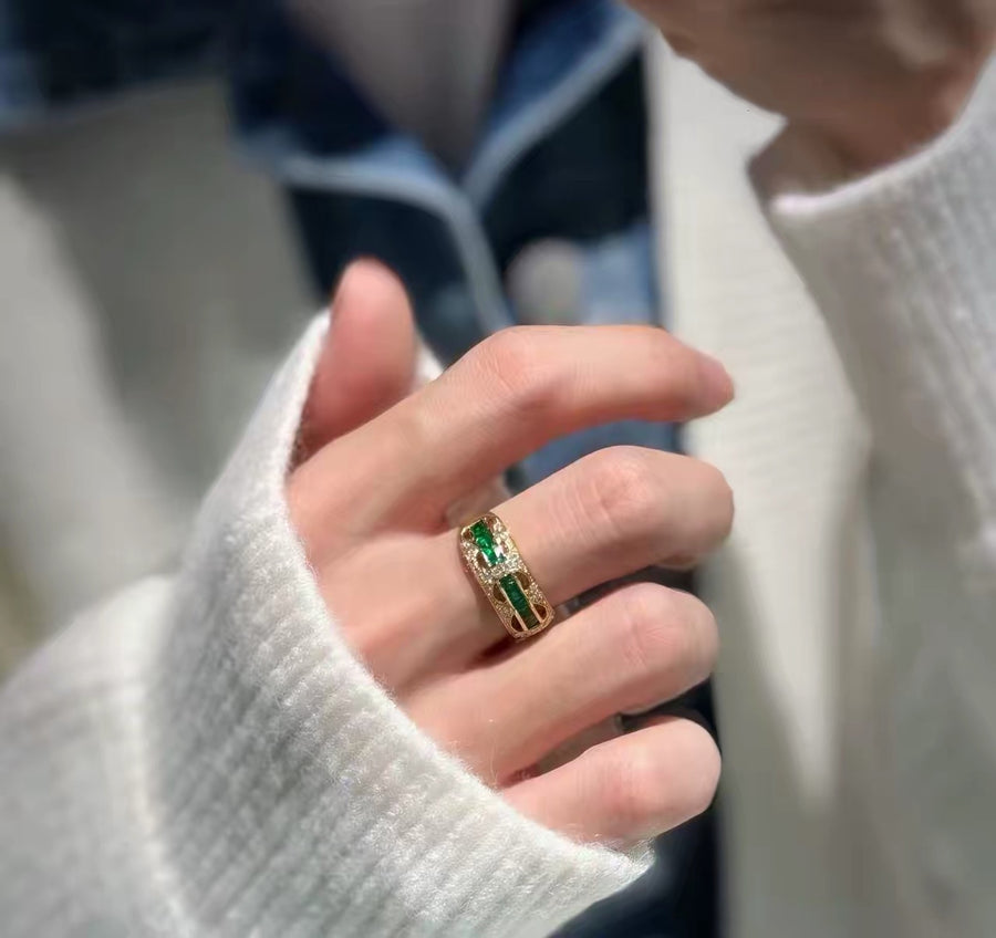 Open band ring with green stones, worn on hand