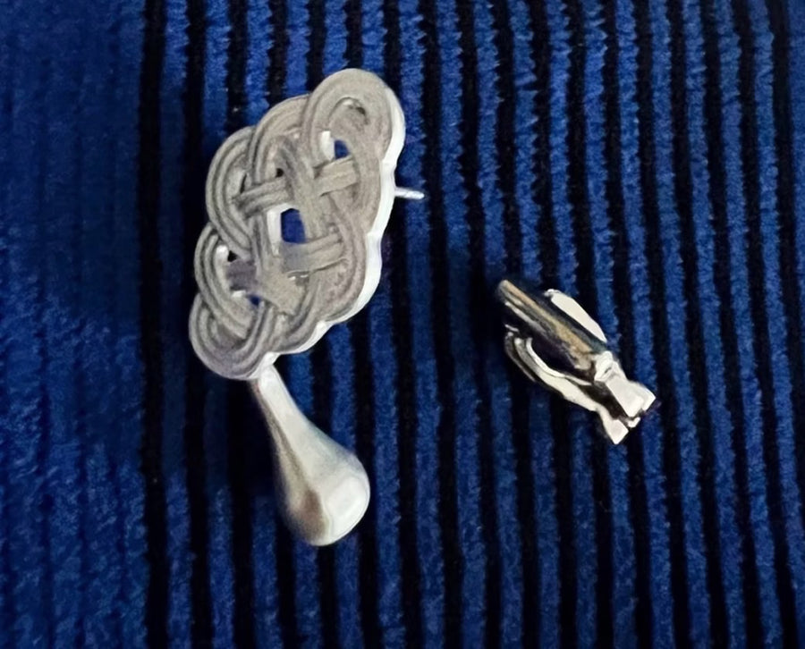Silver-tone knot drop earrings laid flat, showing the posts and backs