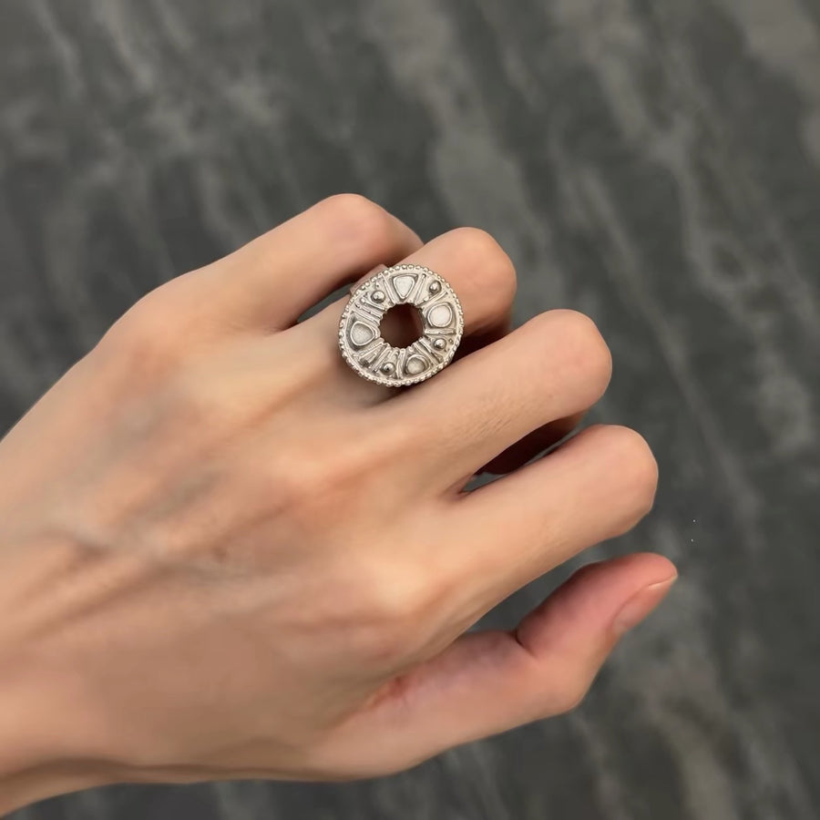 Oval textured silver-tone ring worn on the middle finger